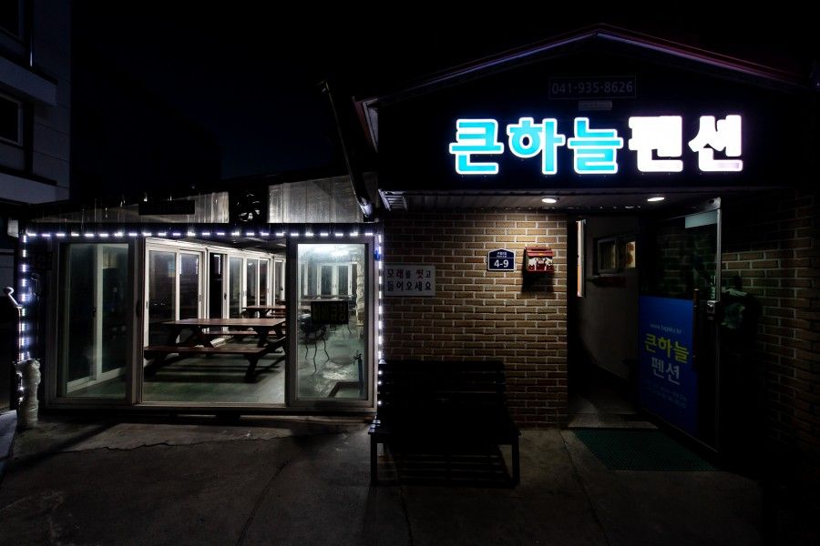 큰하늘펜션 입구와 따뜻하게 불이 켜진 바베큐장